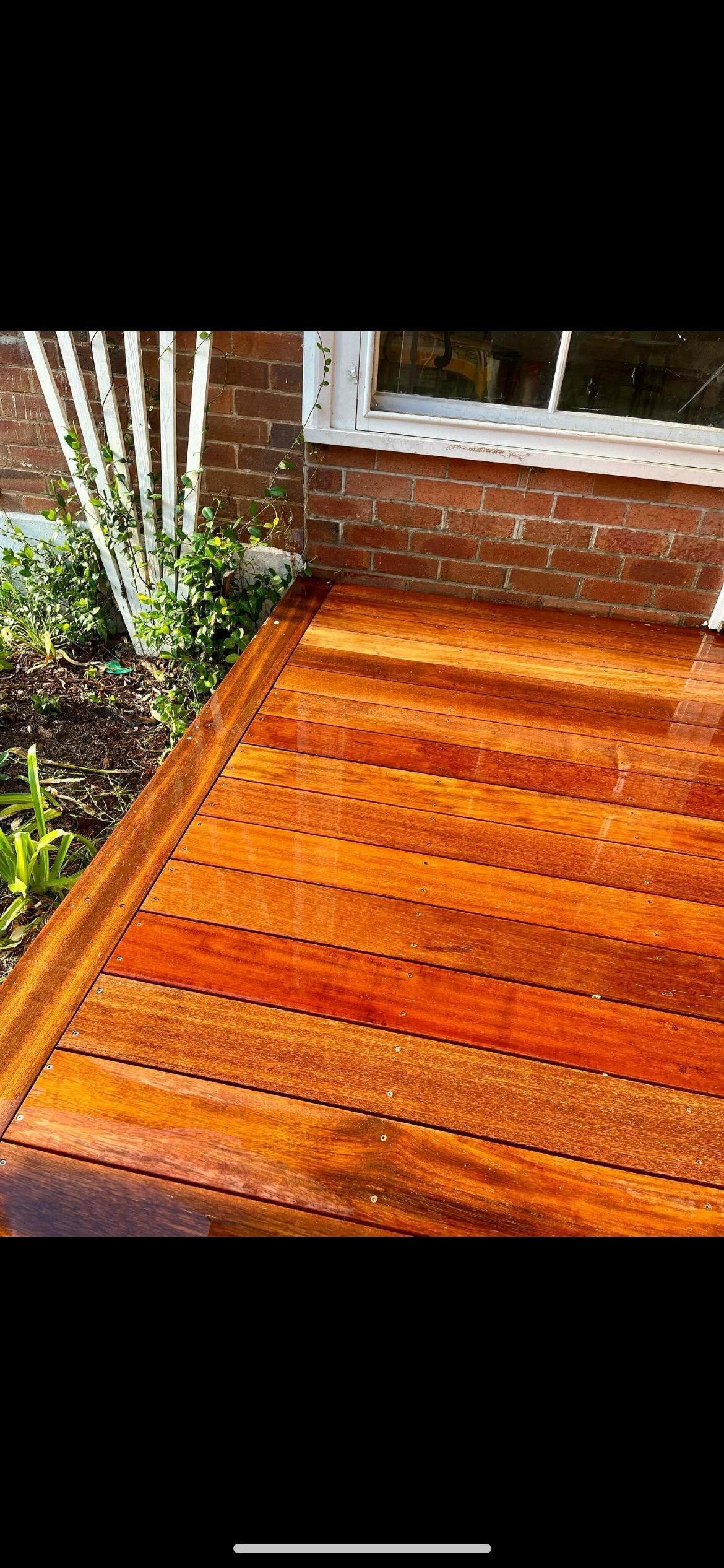 A wooden deck with a brick wall in the background — TM Built Construction In Lochinvar, NSW