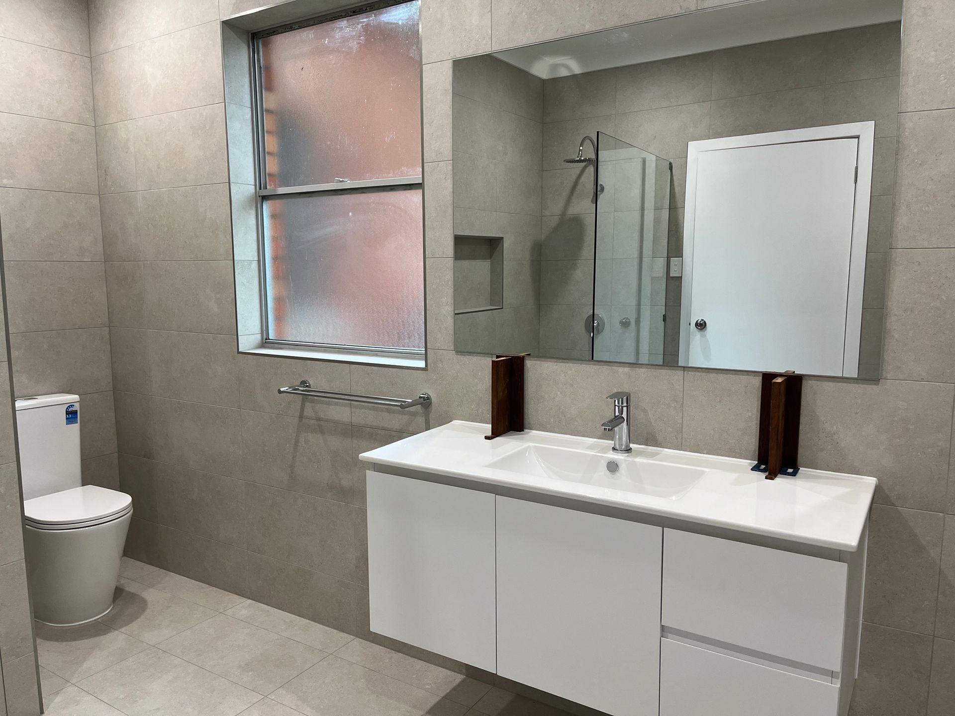 A bathroom with a toilet , sink , mirror and window — TM Built Construction In Lochinvar, NSW