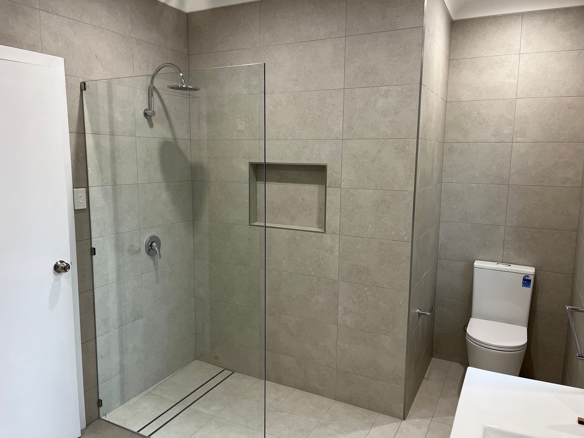 A bathroom with a walk in shower , toilet and sink — TM Built Construction In Lochinvar, NSW