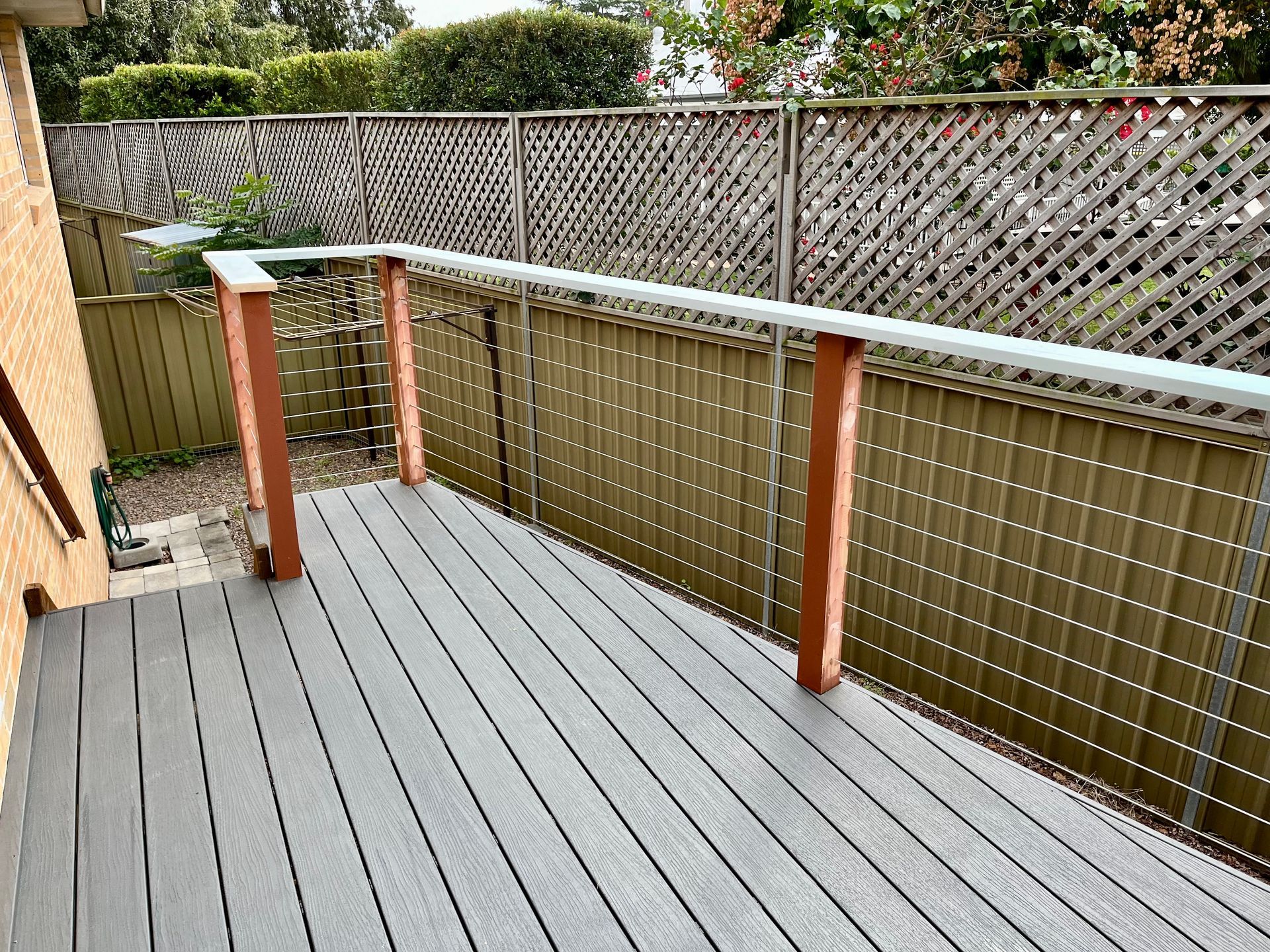 A deck with a wooden railing and a fence in the background — TM Built Construction In Lochinvar, NSW
