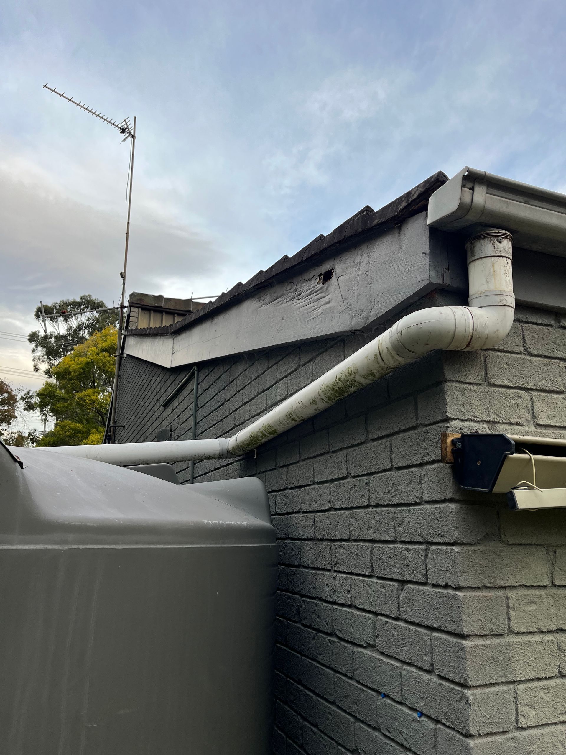 A water tank is attached to the side of a brick building — TM Built Construction In Lochinvar, NSW
