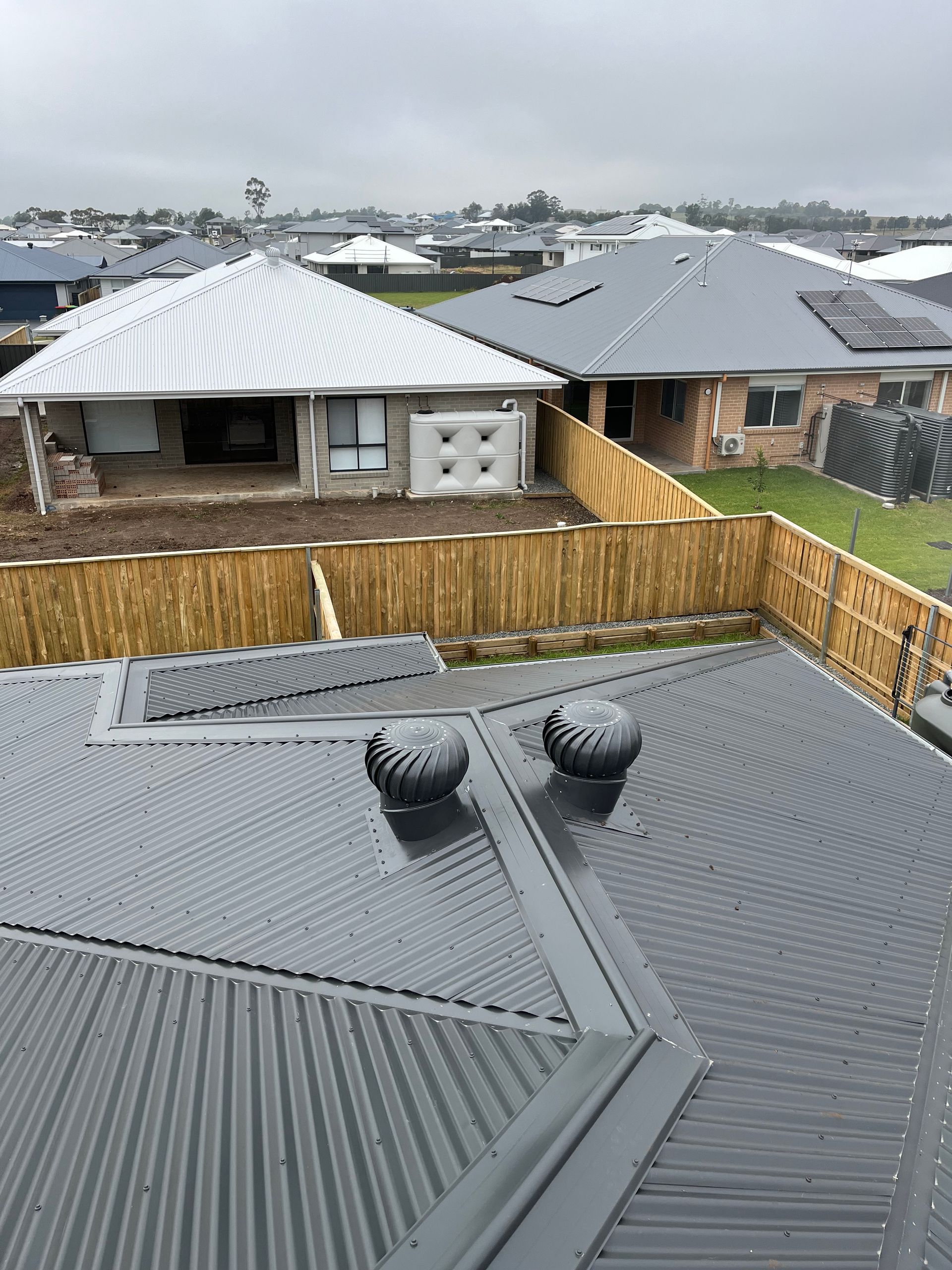 A rooftop view of a residential area with houses and a fence — TM Built Construction In Lochinvar, NSW