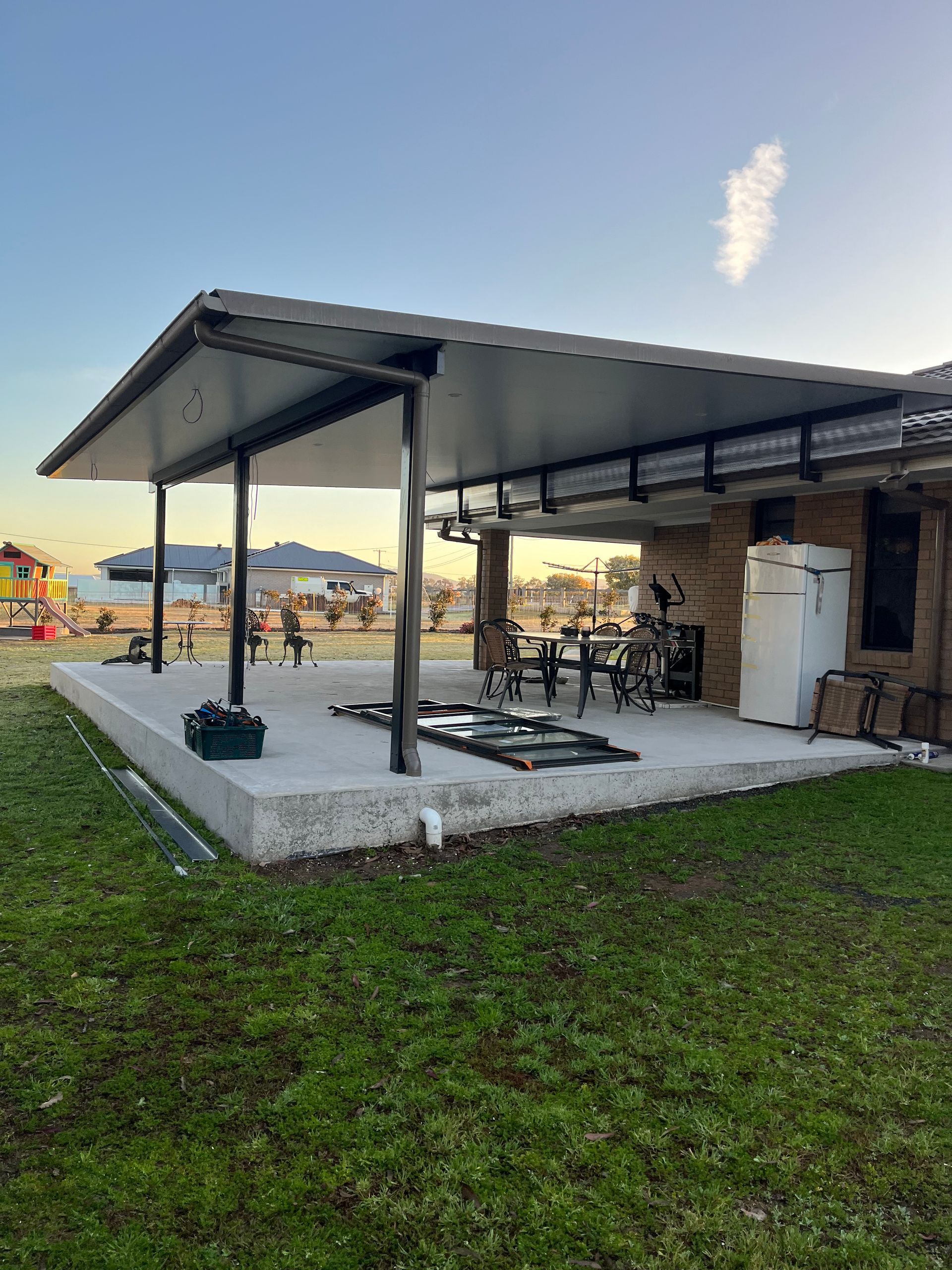 A patio with a roof and a table and chairs underneath it — TM Built Construction In Lochinvar, NSW
