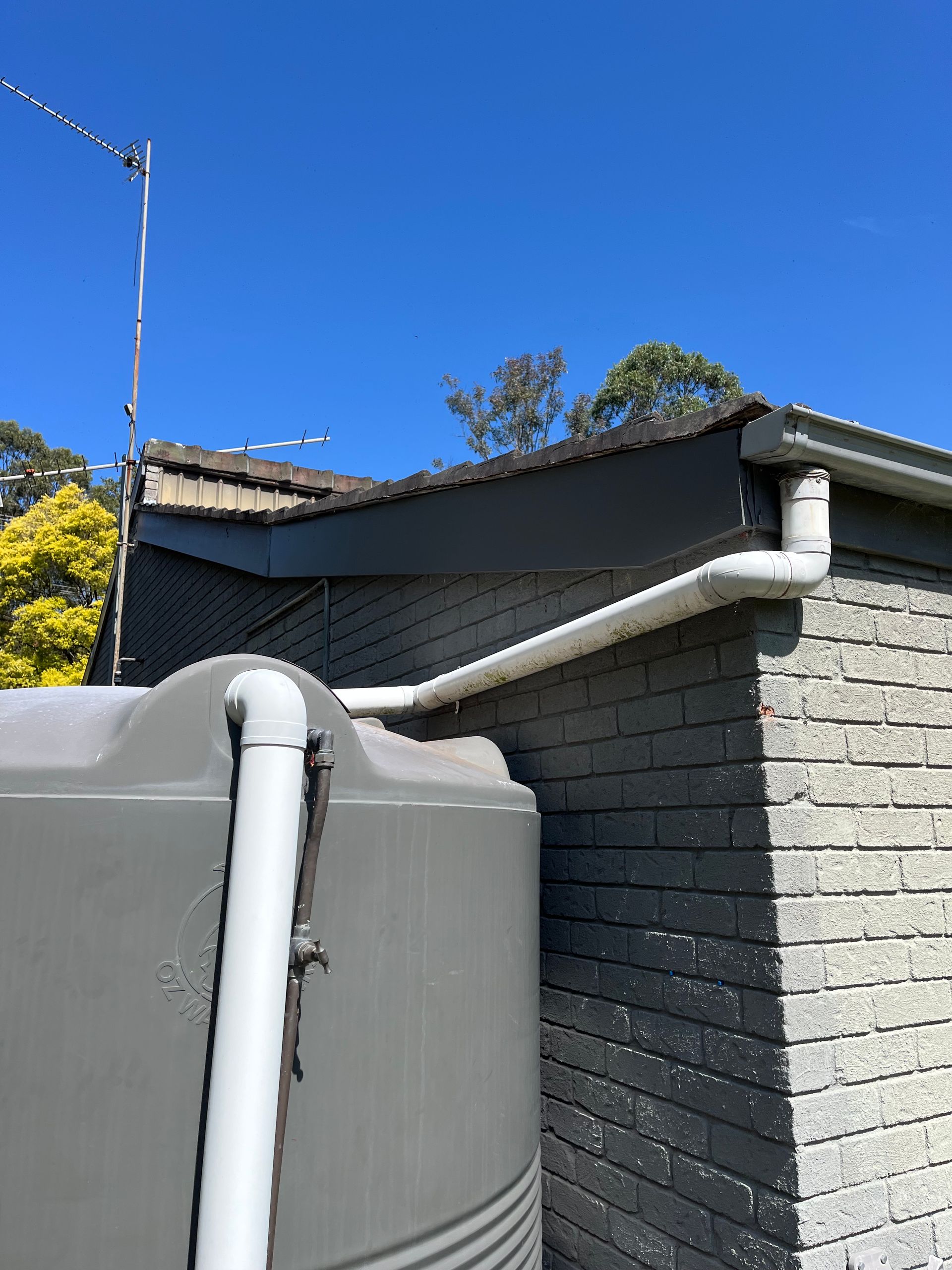 A water tank is attached to the side of a brick building — TM Built Construction In Lochinvar, NSW