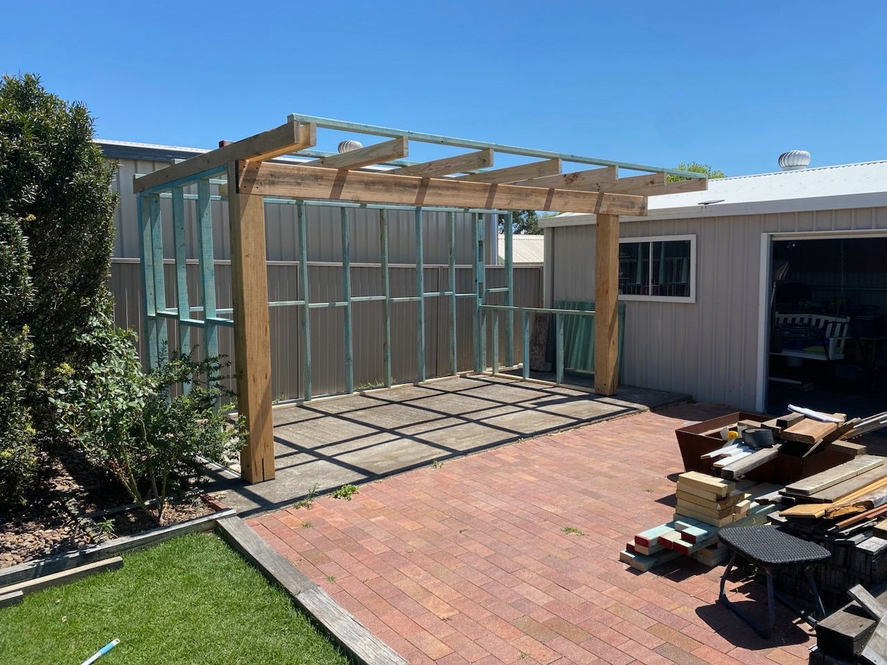 A wooden pergola is being built in the backyard of a house — TM Built Construction In Lochinvar, NSW