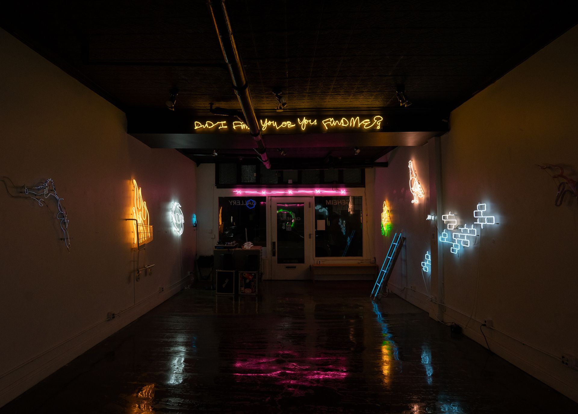 Interior of Geheim Gallery with neon light art installations by Yale Wolf. Dark space with illuminated walls and a doorway.