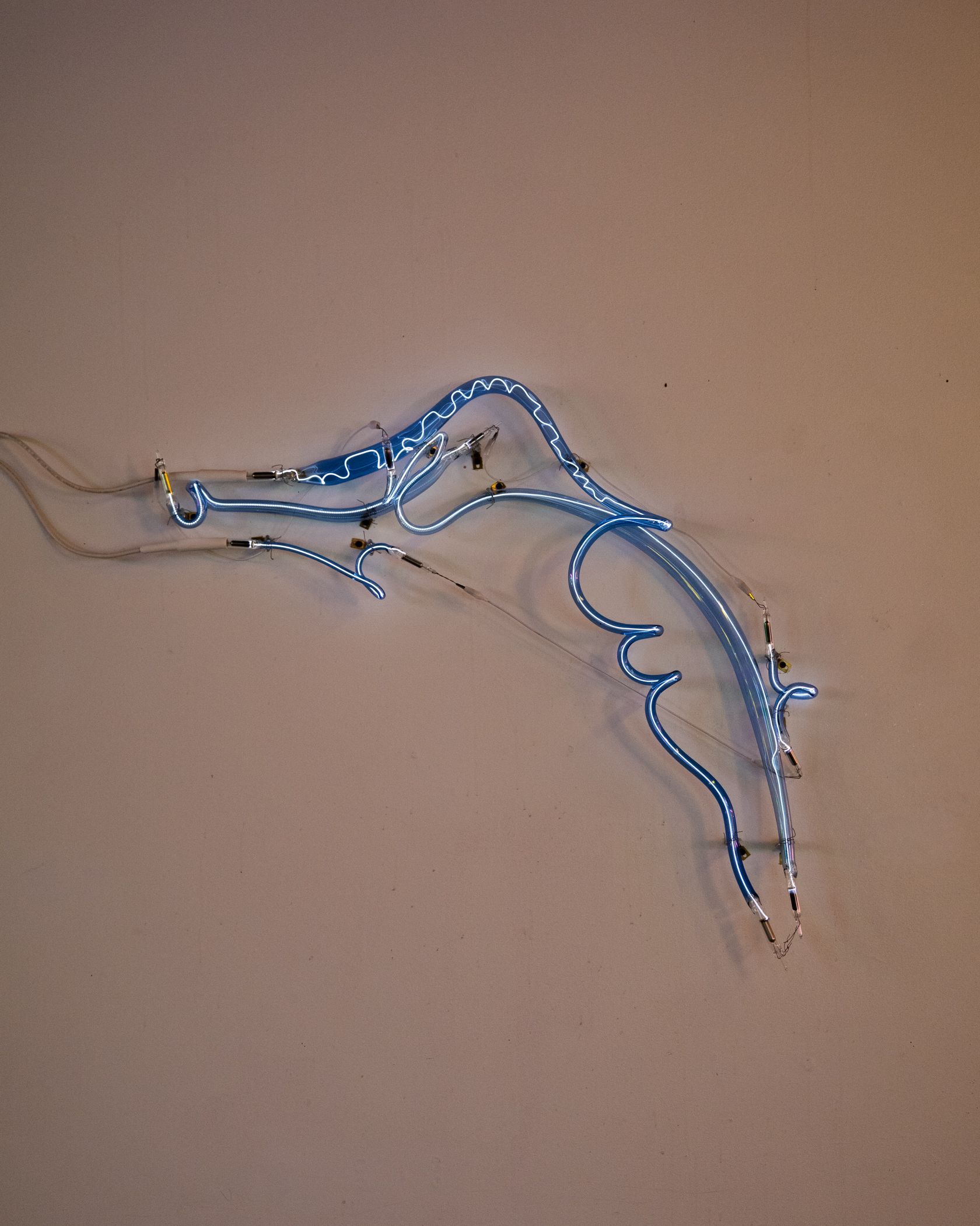 Blue neon light shaped like the Florida state outline mounted on a beige wall.