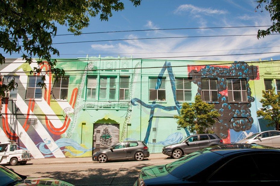 Colorful mural on building with cars parked on street.