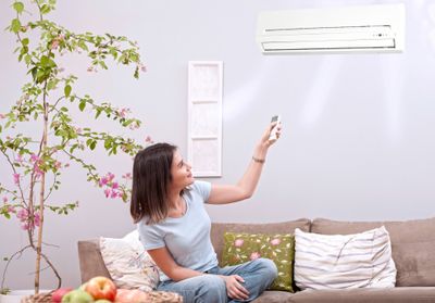 Woman Adjusting Air Conditioner — Everett, WA — Eylander Electric