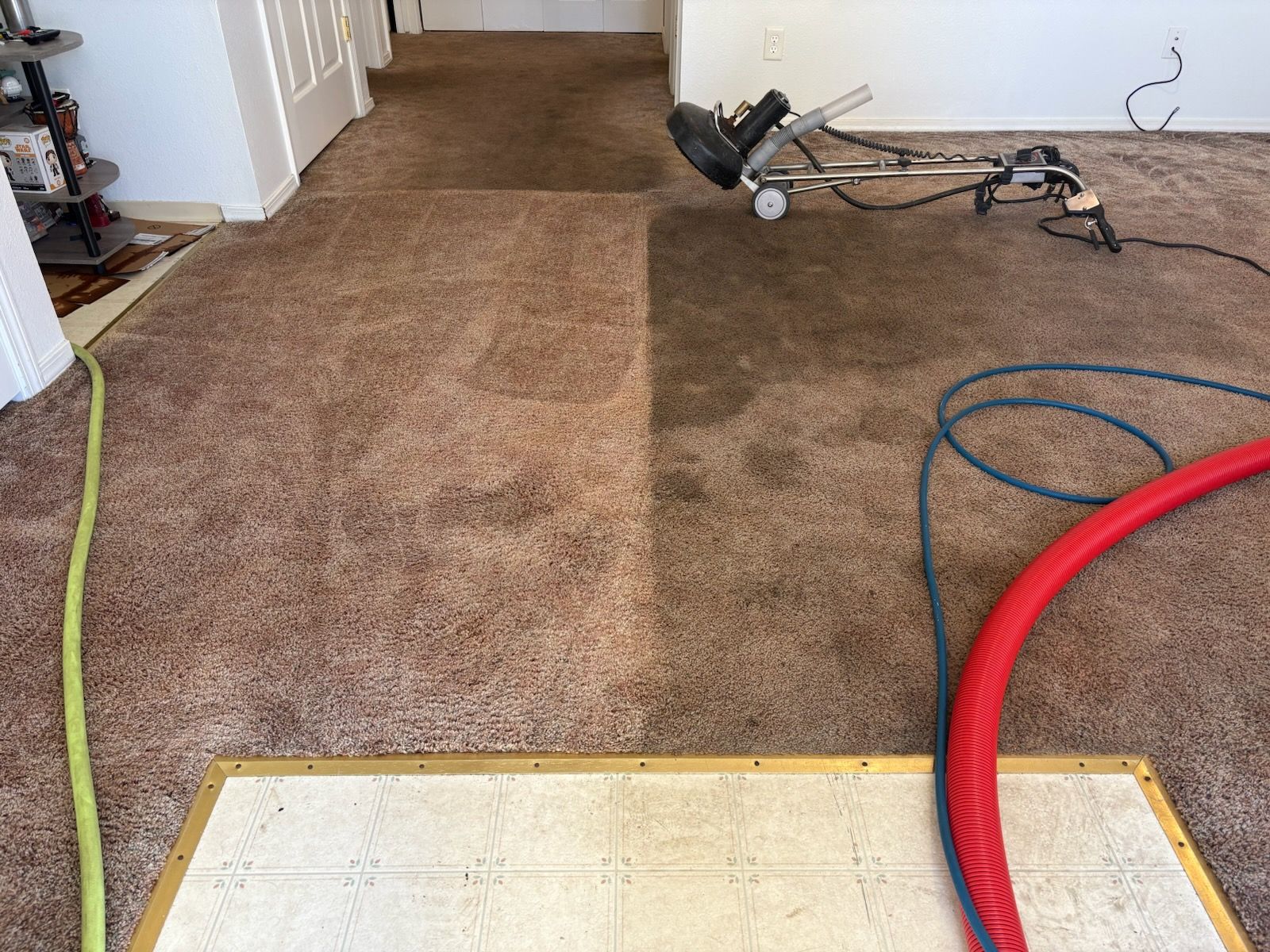Carpeted hallway under repair with a floor sander, hoses, and a white carpet strip in the foreground