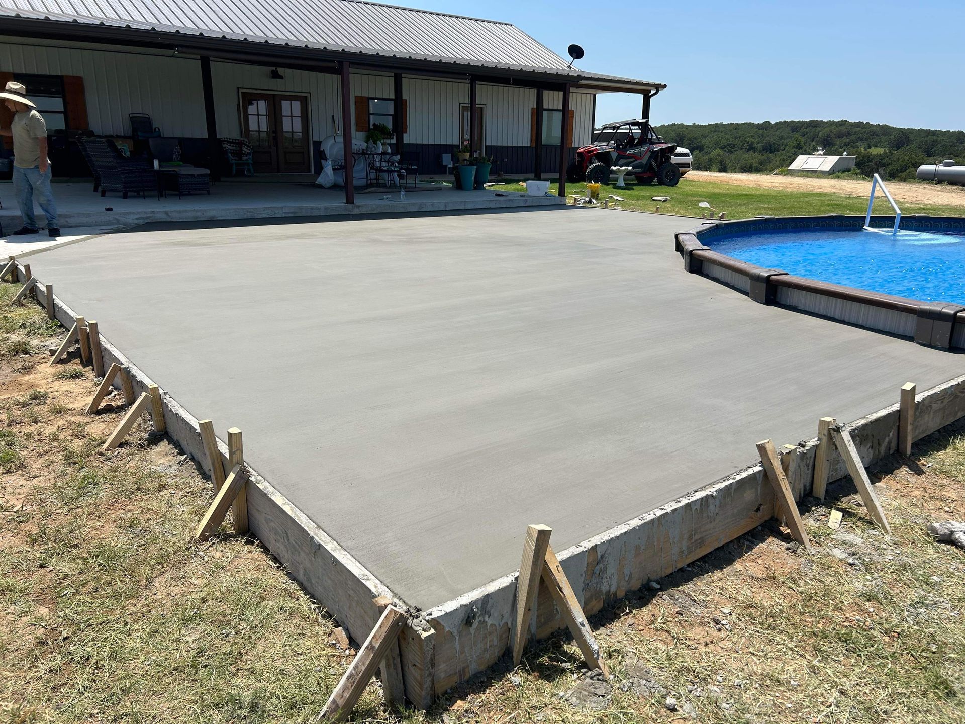 A concrete driveway is being built next to a pool.
