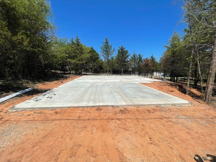 A large concrete slab is sitting in the middle of a dirt road surrounded by trees.