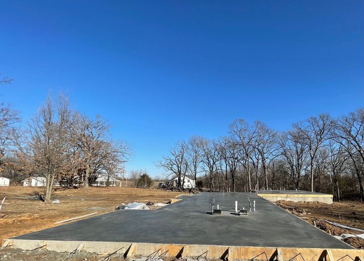 A concrete driveway is being built in a field with trees in the background.