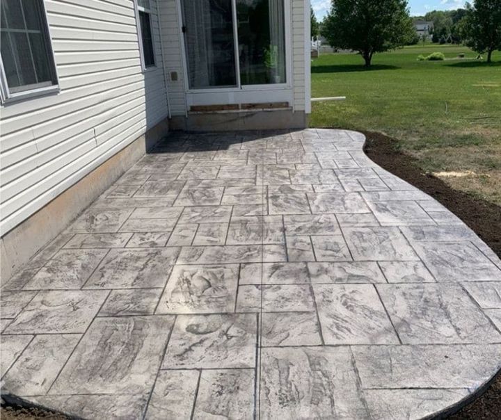 A concrete patio in front of a house with a sliding glass door.