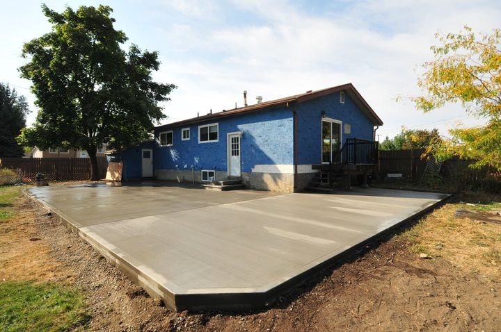 A blue house with a concrete driveway in front of it