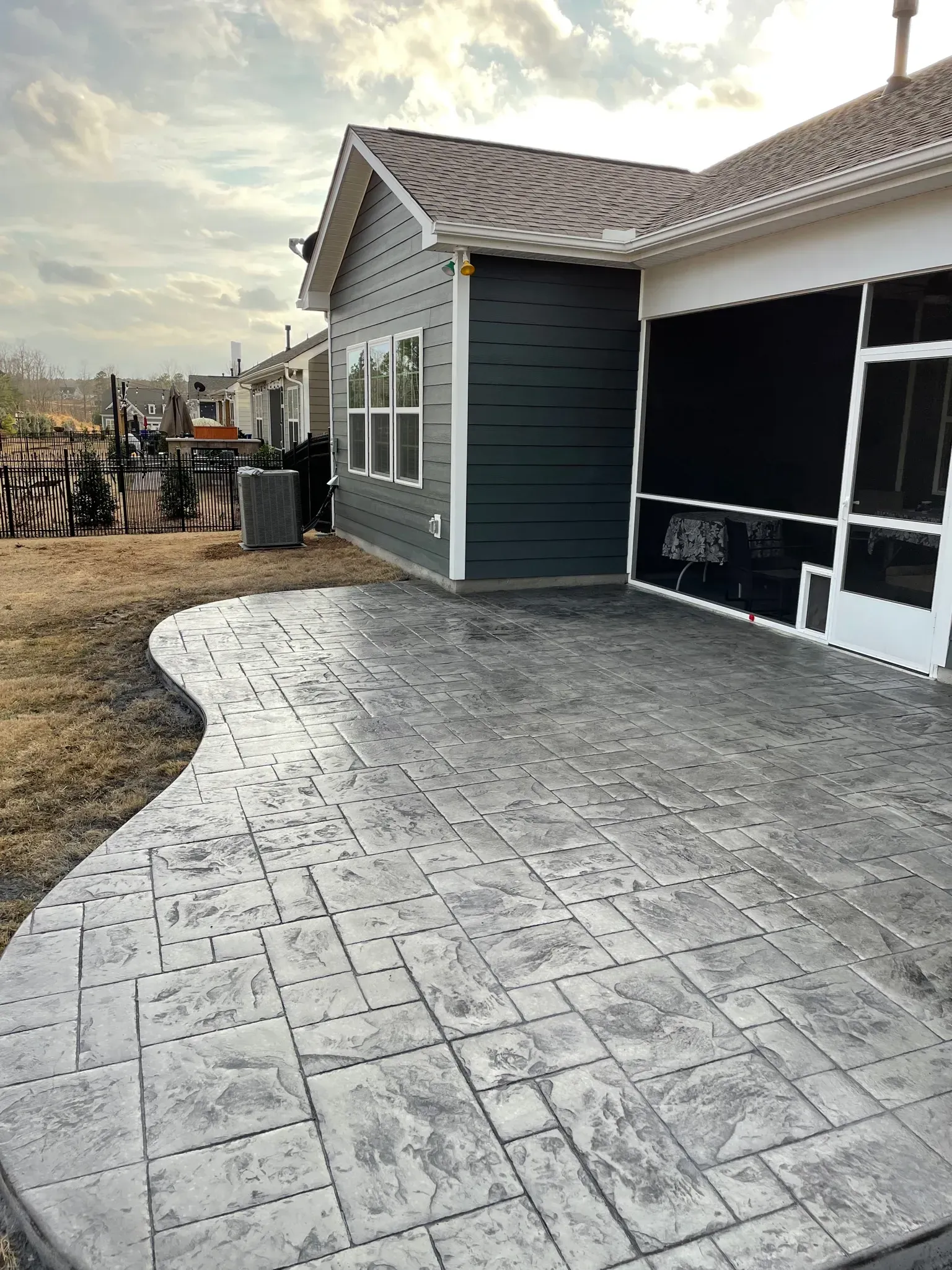 A house with a screened in porch and a concrete patio in front of it.