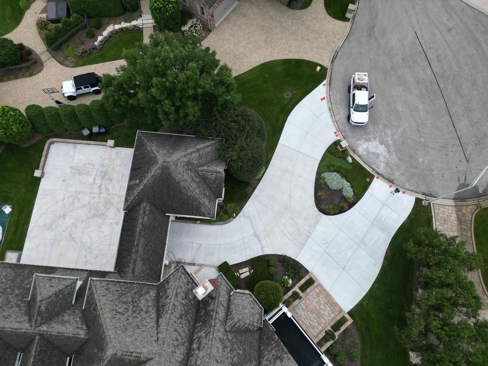 An aerial view of a white house with a concrete driveway leading to it.