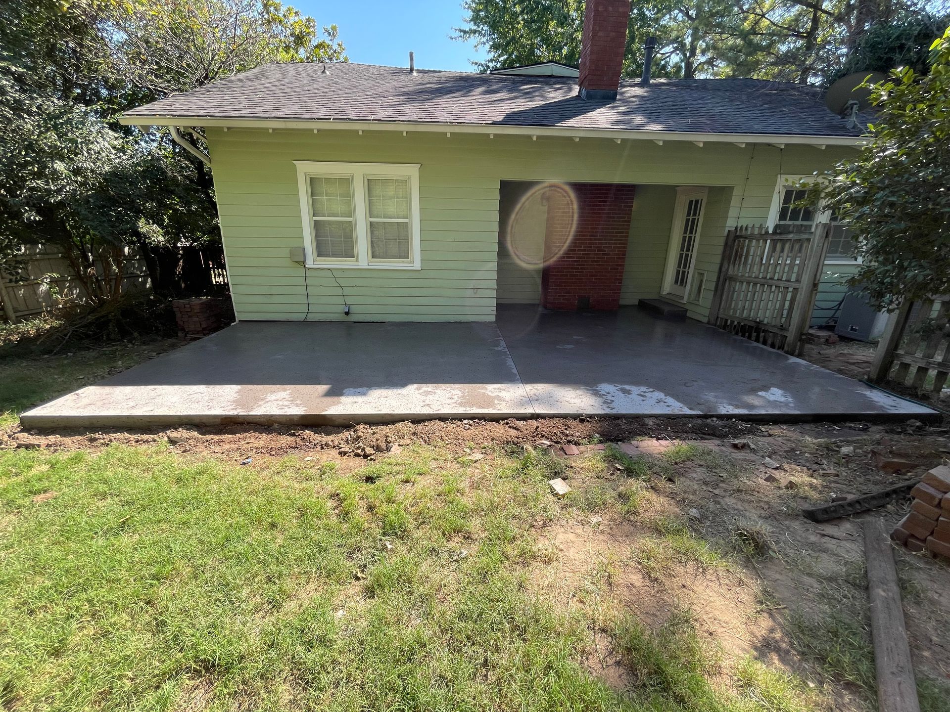 A small green house with a concrete patio in front of it.