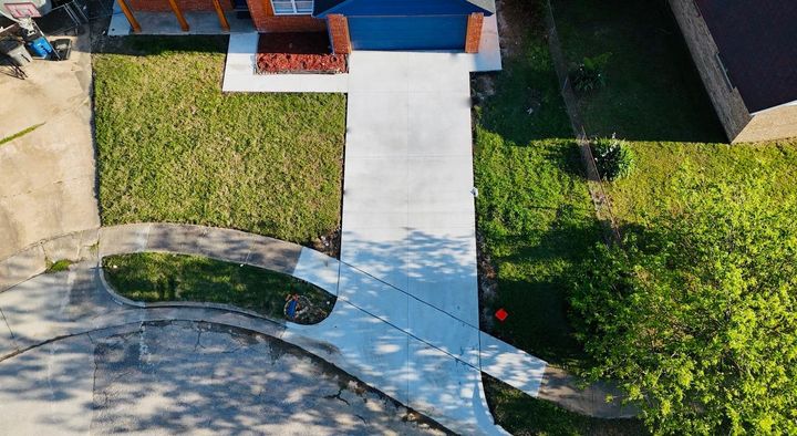 A concrete driveway leading to a mailbox in the middle of a field.