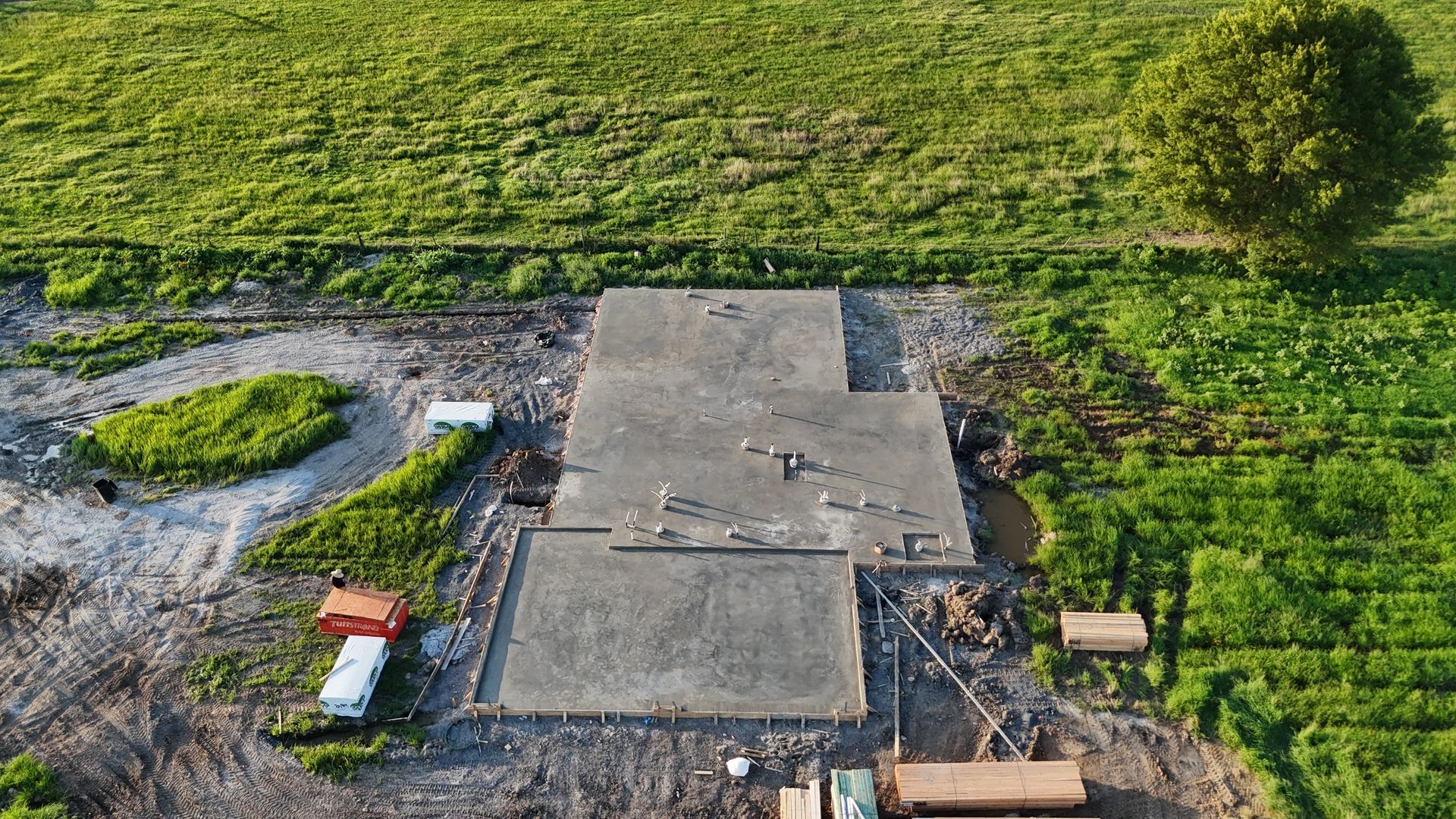 An aerial view of a house under construction in the middle of a dirt field.