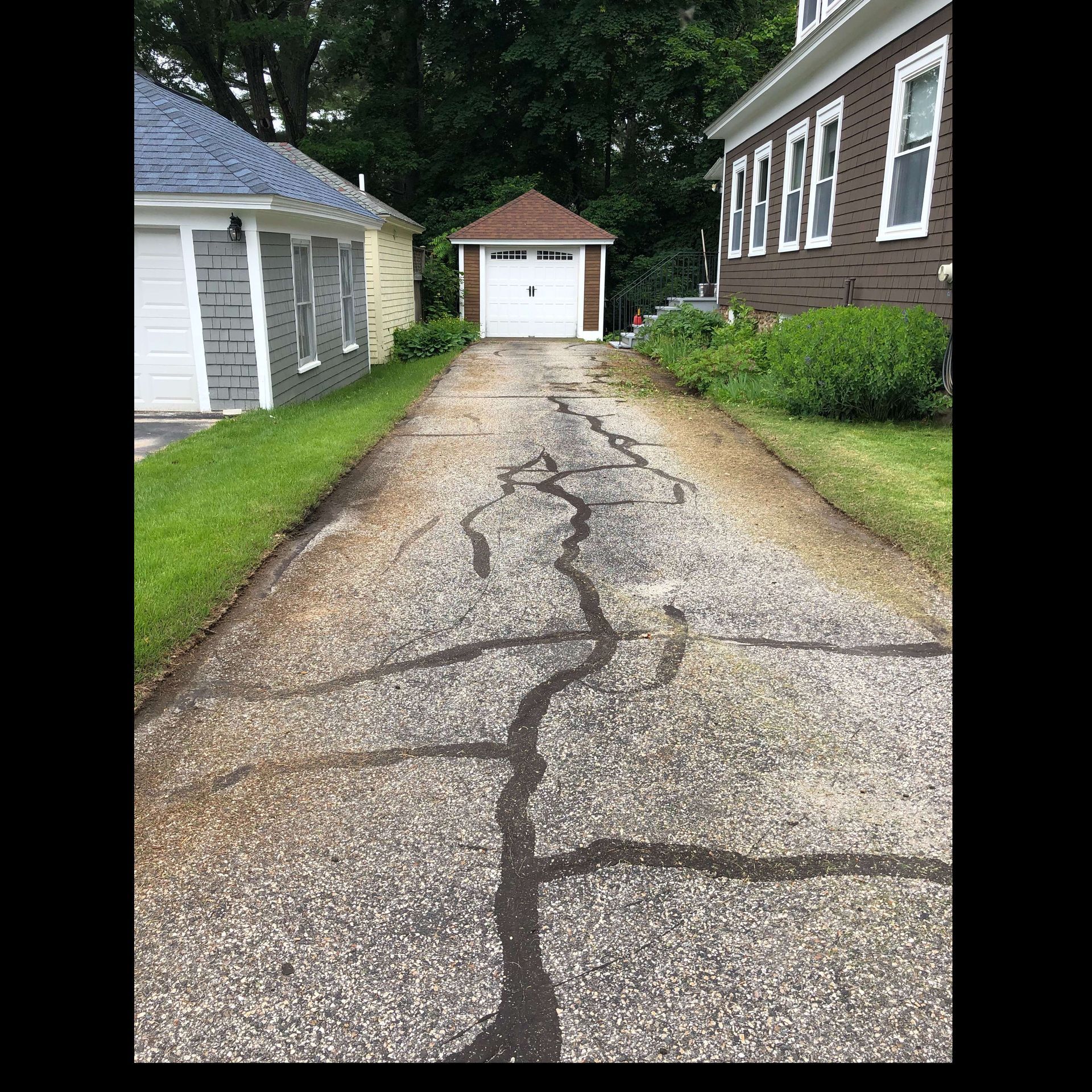 A cracked driveway leading to a house with a garage.