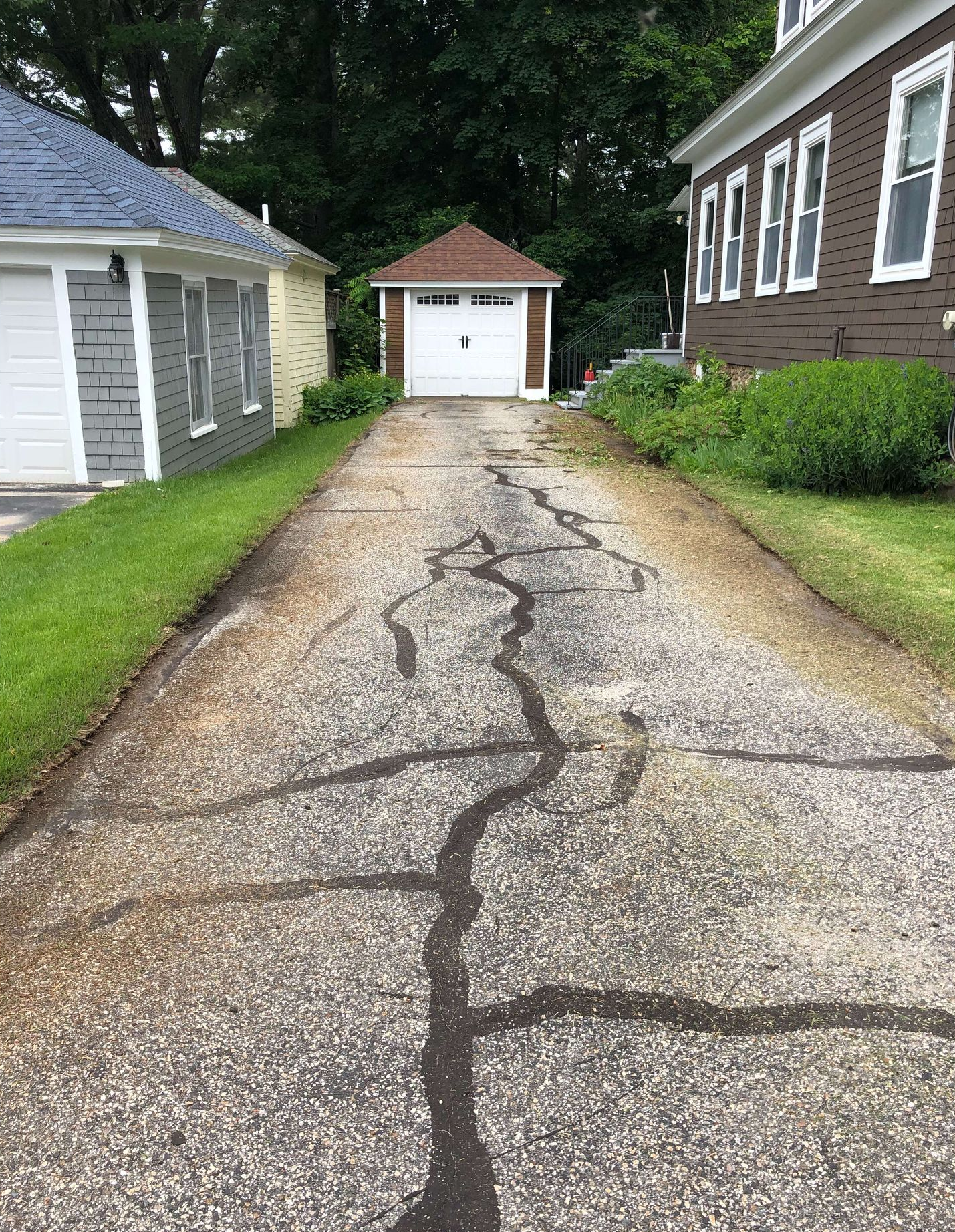 A cracked driveway leading to a house with a garage.