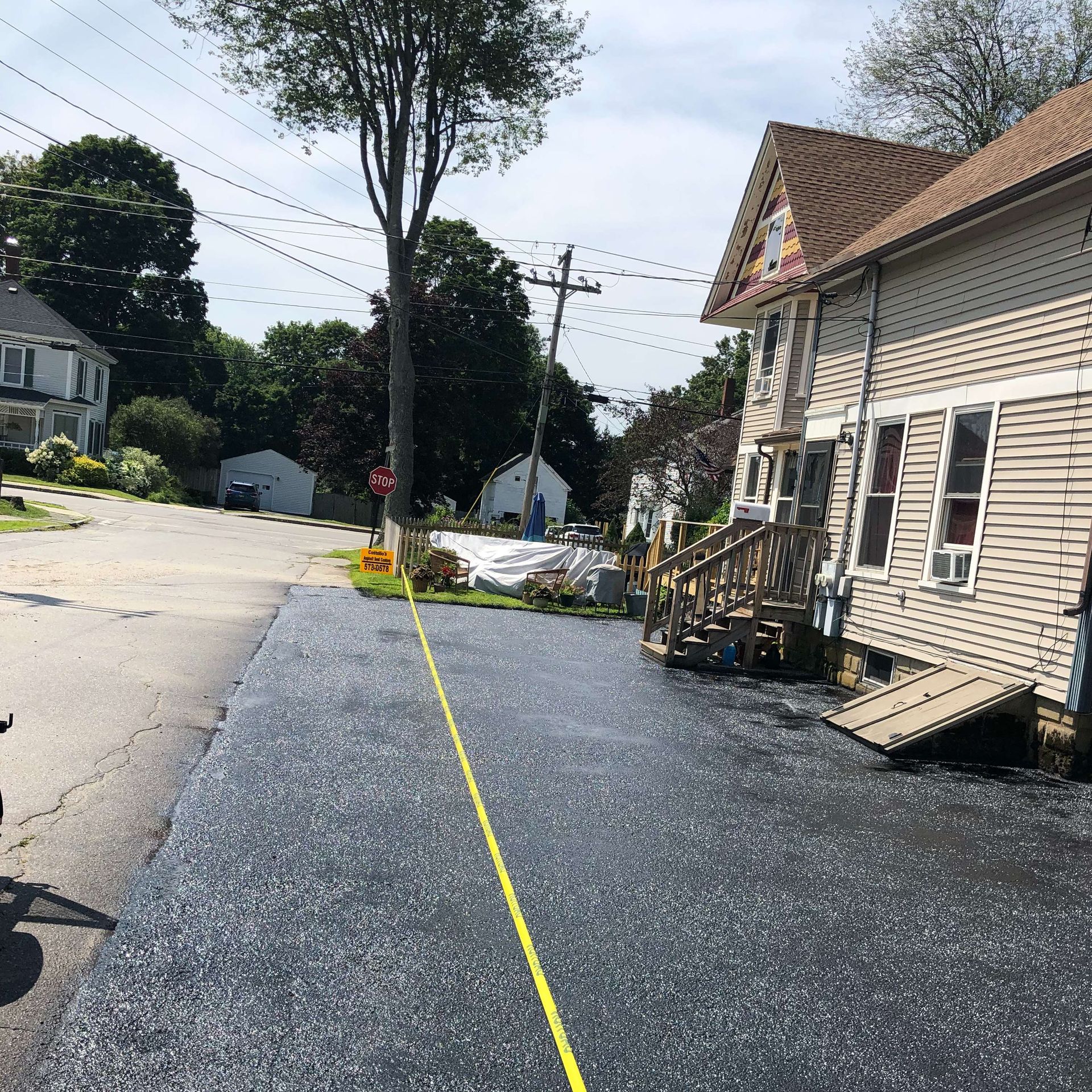 A yellow line is being drawn on the side of a road in front of a house.