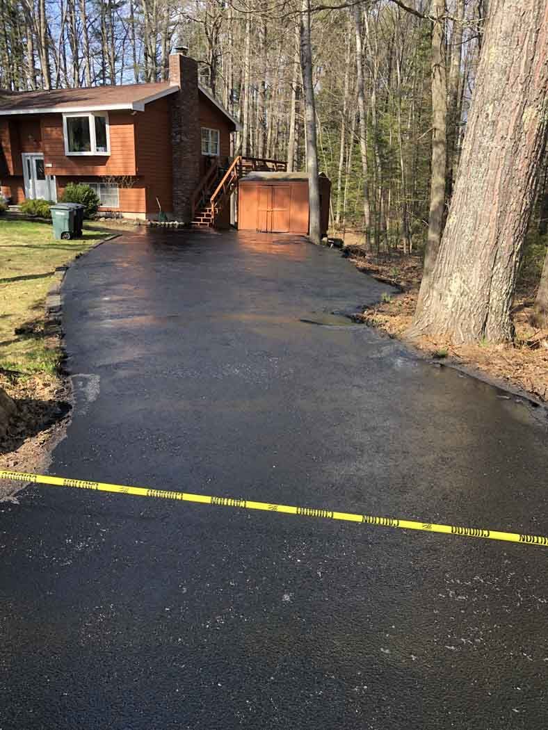 A driveway leading to a house in the woods.