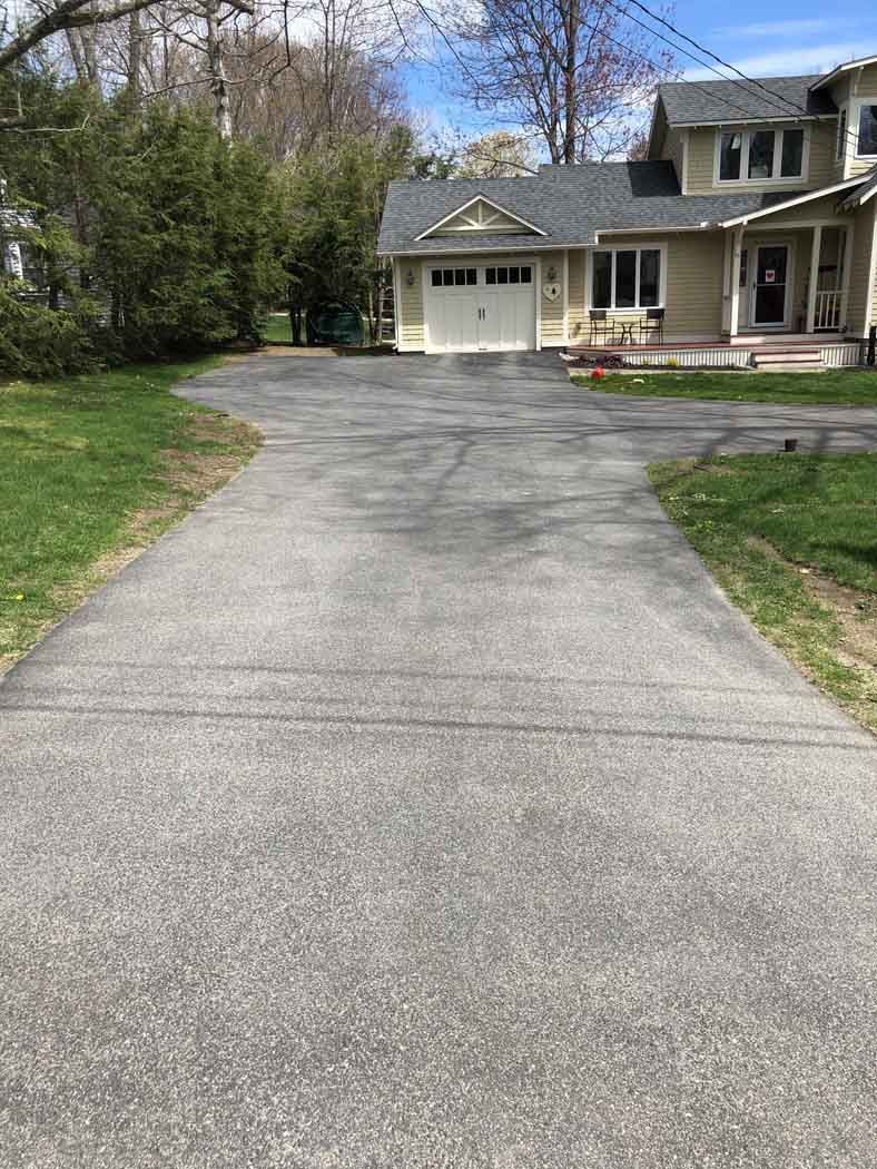 A concrete driveway leading to a house with a garage.