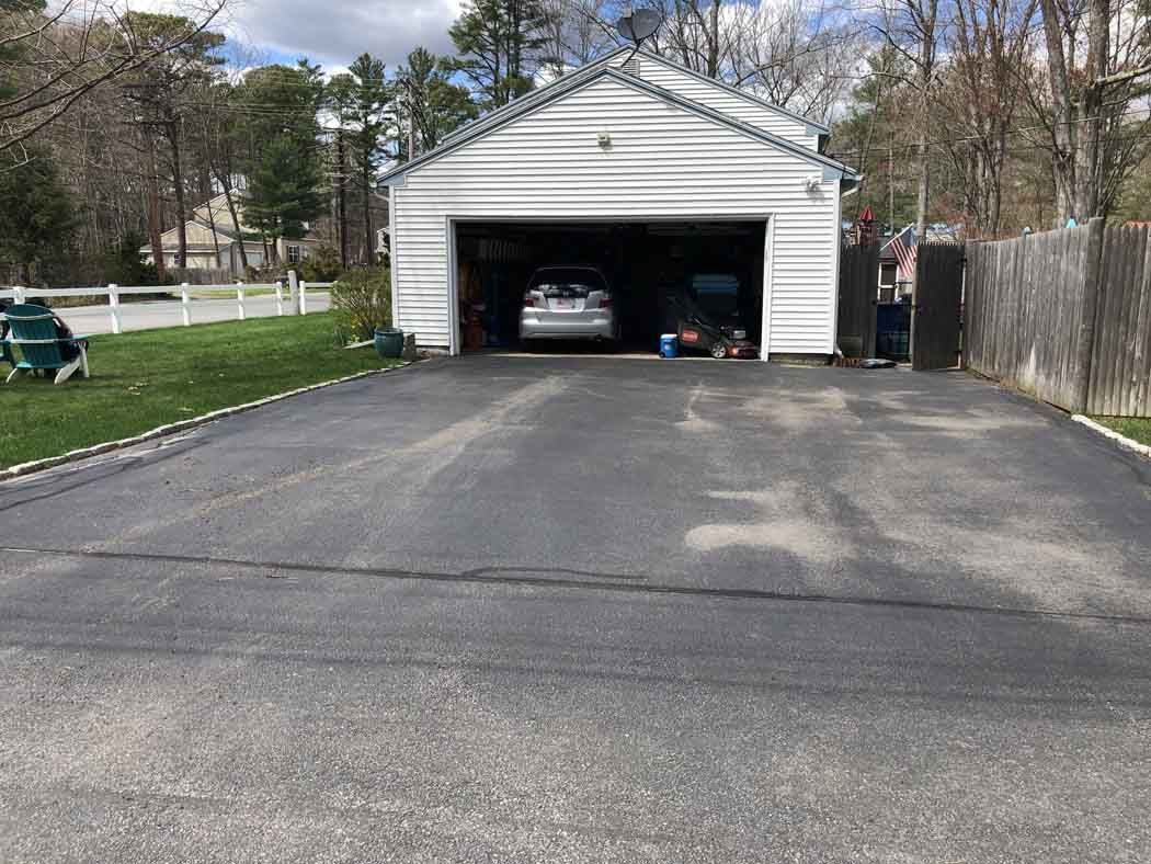 A car is parked in a garage next to a driveway.