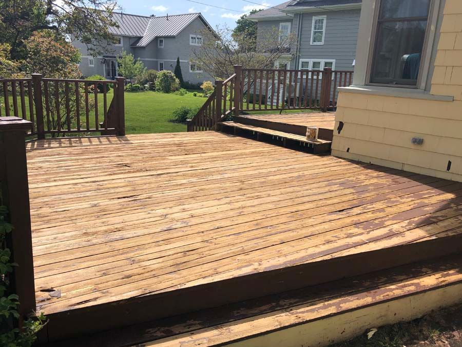 A wooden deck with stairs leading up to it is in front of a house.