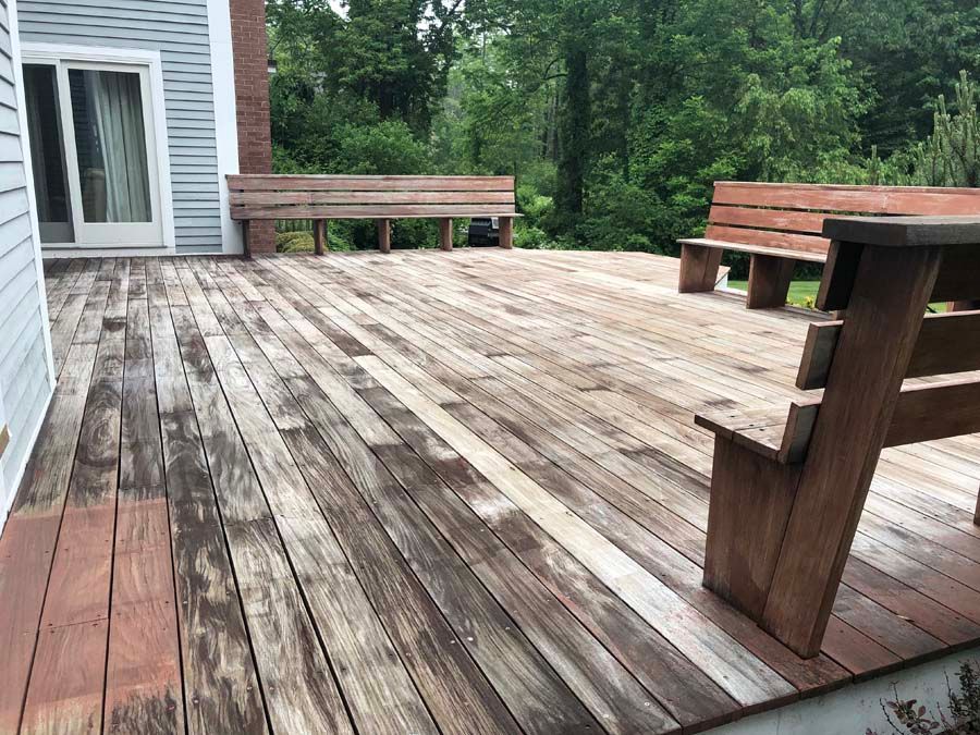 A wooden deck with a picnic table and benches on it.