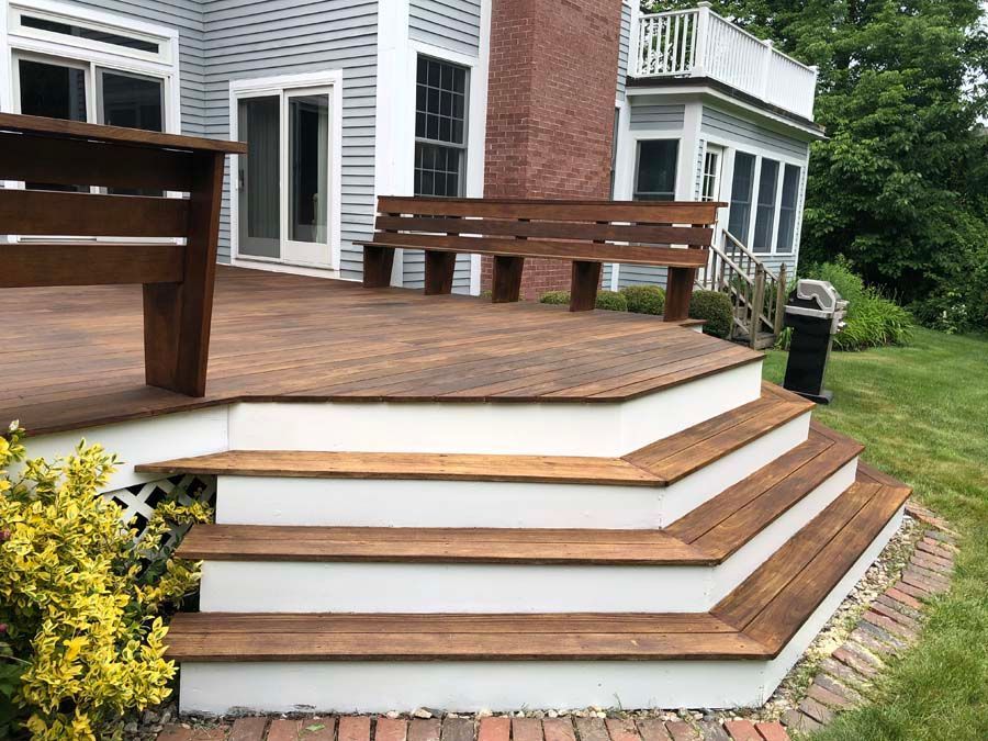 A wooden deck with stairs leading up to it in front of a house.