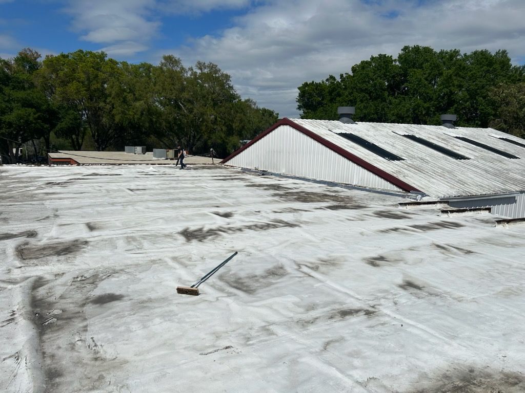 Back yard with a light yellow building, fence, and paved surface.