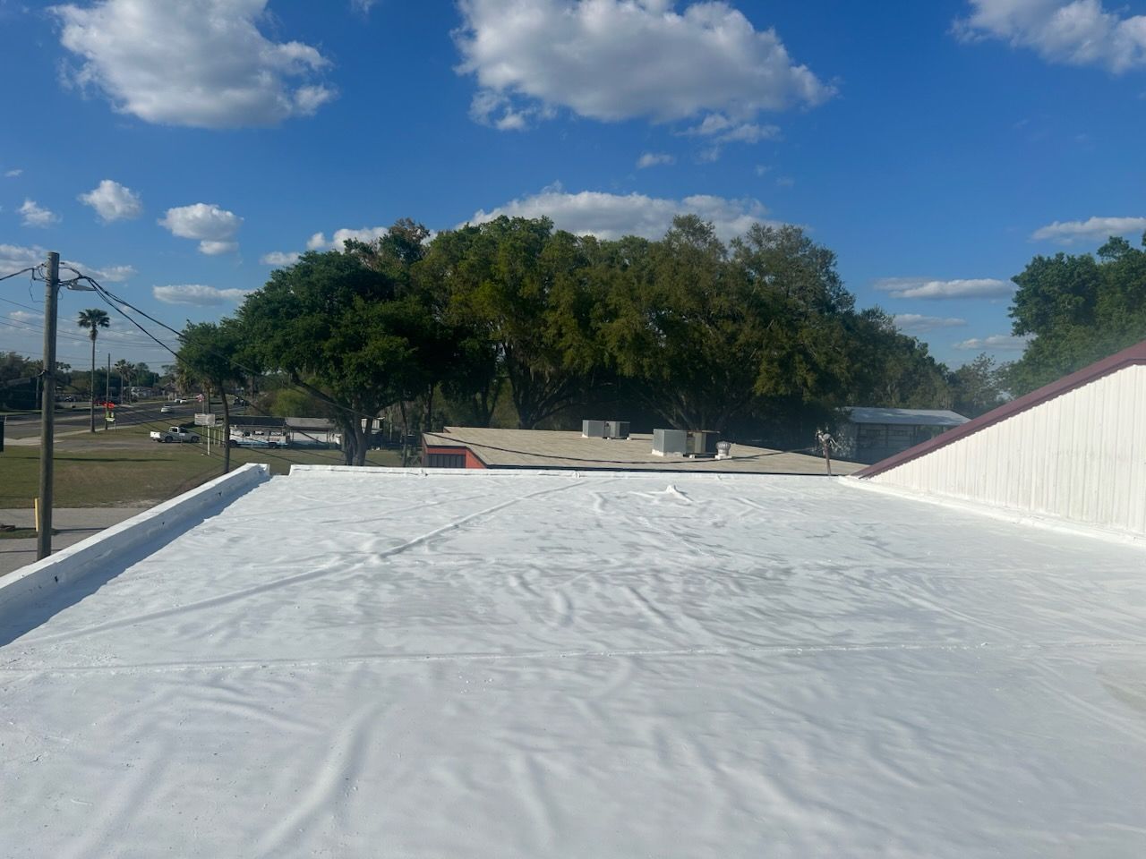 Person in neon green hoodie on hands and knees examining a crack in a newly paved parking lot.