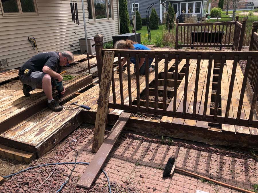 A group of people are working on a wooden deck.