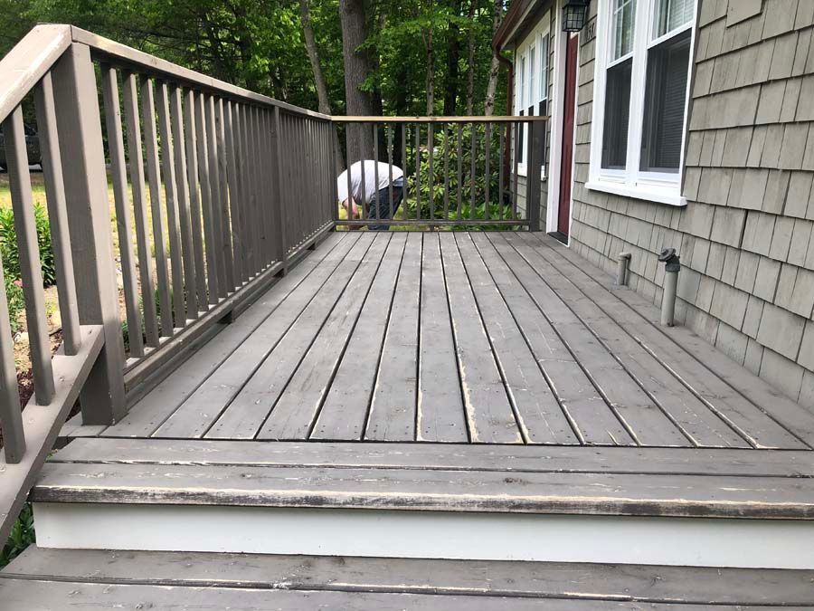 A man is standing on a wooden deck next to a house.