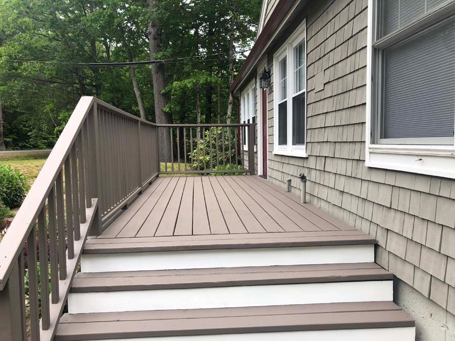A deck with stairs leading up to it is on the side of a house.