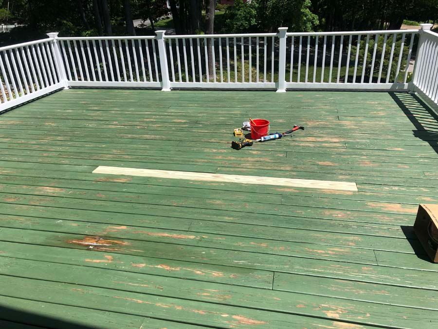 A green deck with a white railing and a bucket on it.