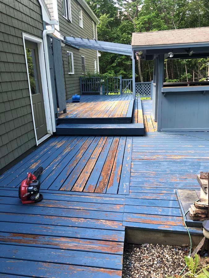A blue deck with a shed in the background and a house in the background.