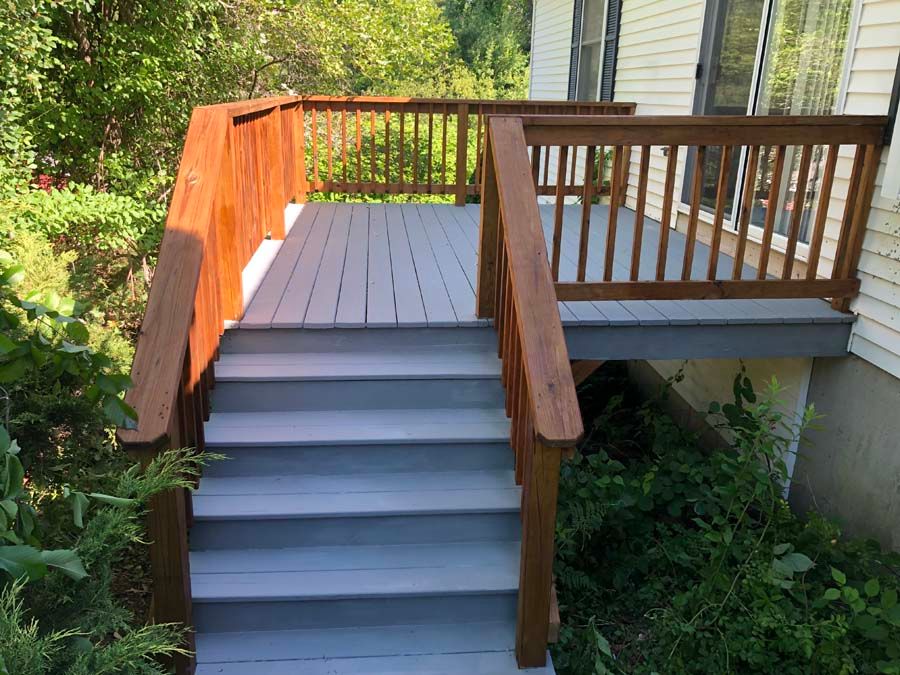 A wooden deck with stairs leading up to it in front of a house.