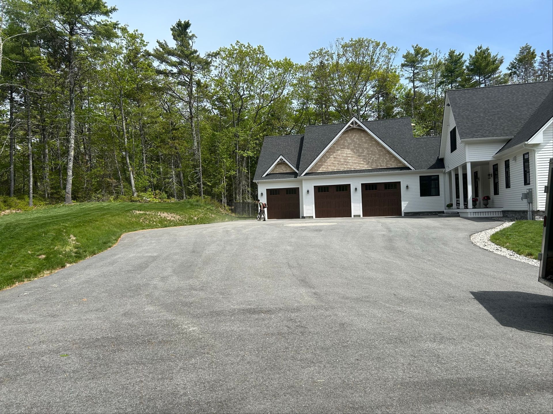 Back yard with a light yellow building, fence, and paved surface.