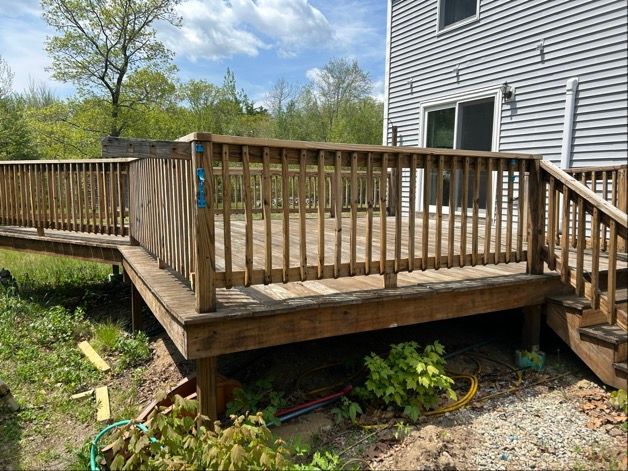Back yard with a light yellow building, fence, and paved surface.