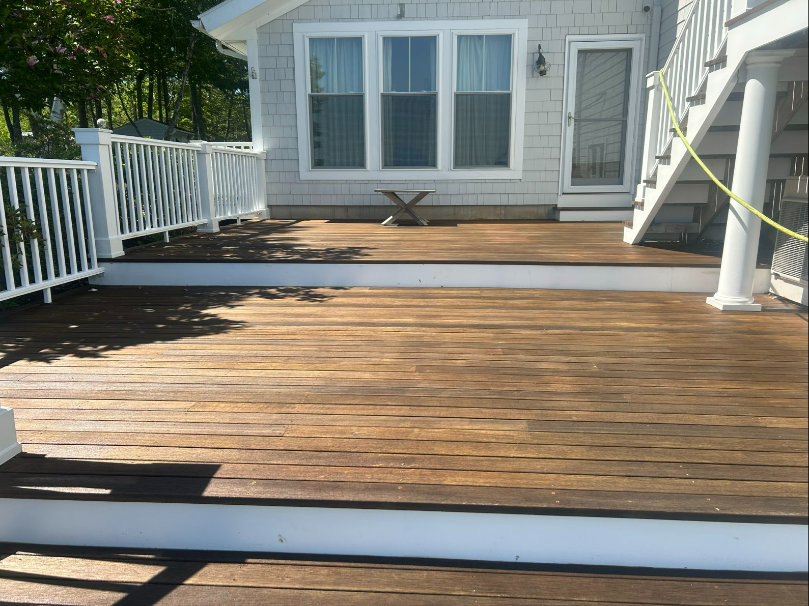 Back yard with a light yellow building, fence, and paved surface.