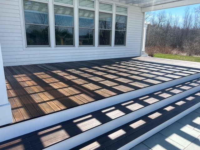 A wooden deck with stairs leading up to it in front of a house.