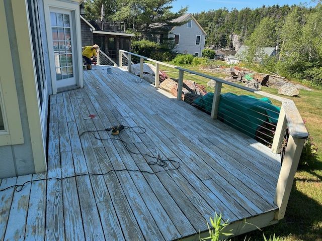 A blue deck with a shed in the background and a house in the background.
