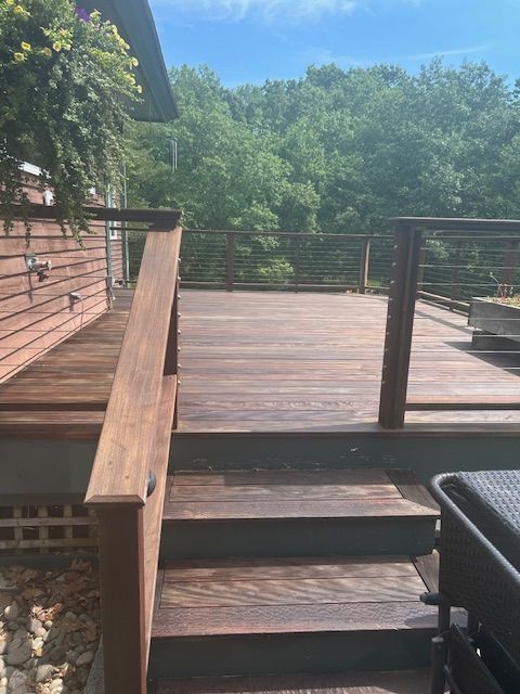 A wooden deck with stairs leading up to it and a house in the background.