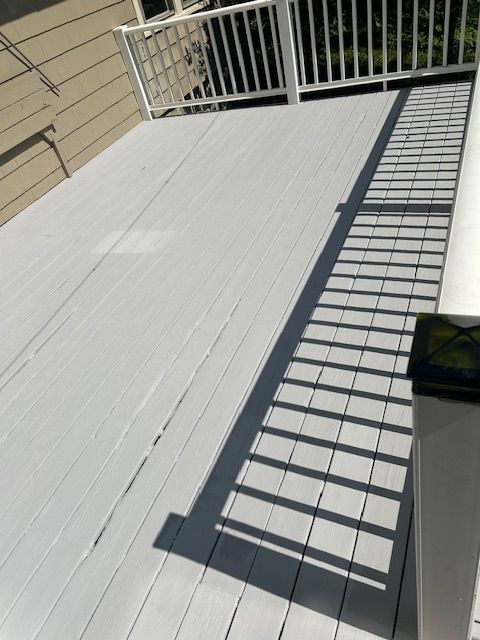 A wooden deck with stairs leading up to it and a house in the background.