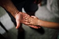 A man and a child are holding hands.