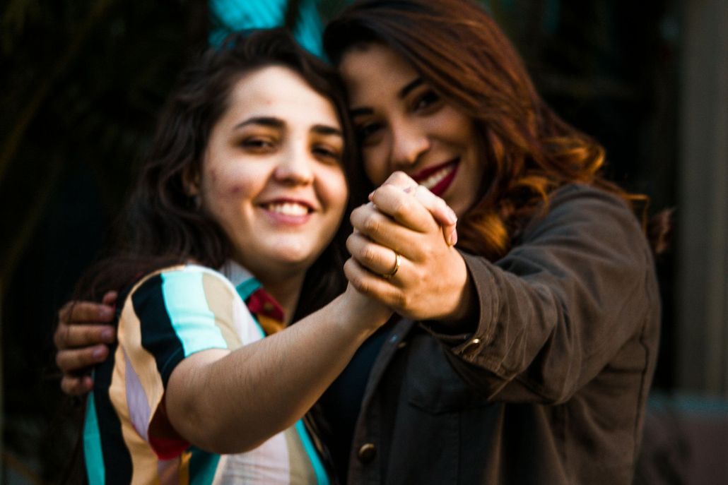 Two women are holding hands and hugging each other.